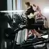 A row of treadmills with two students running on those furthest away