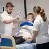 Three students stood around a physiotherapy patient in a hospital bed