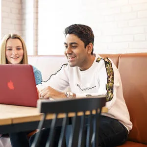 Two students gathered around a laptop