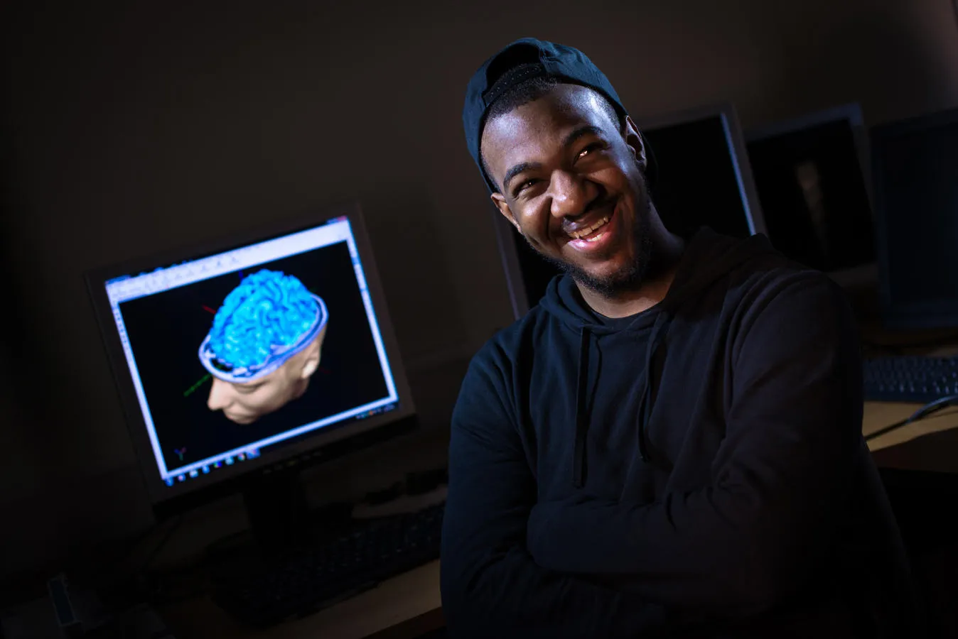 Aaron Hall Psychology student sat in front of a computer showing a medical scan of a brain