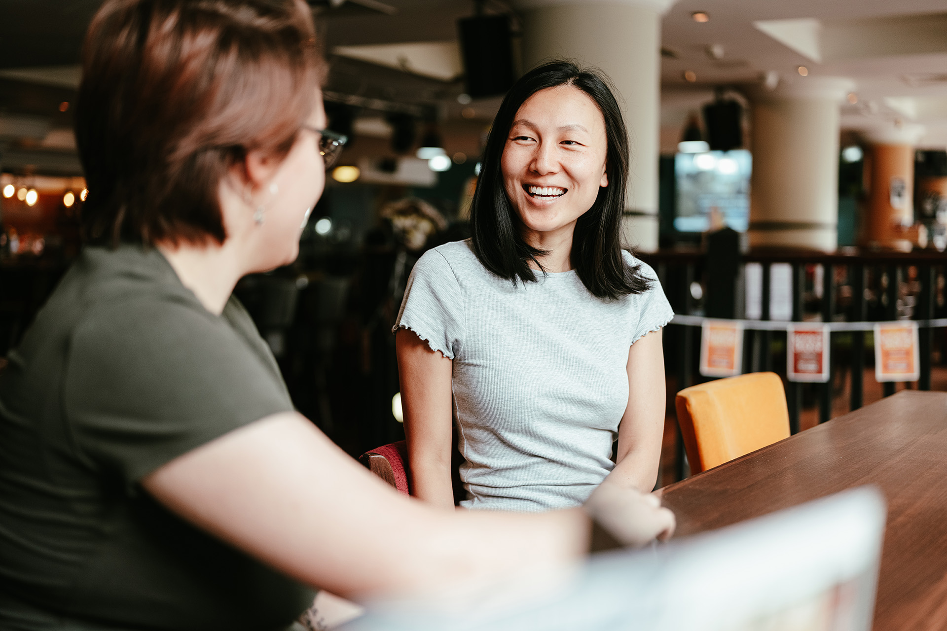 Two women seated at a table, actively discussing and exchanging thoughts in a friendly atmosphere.