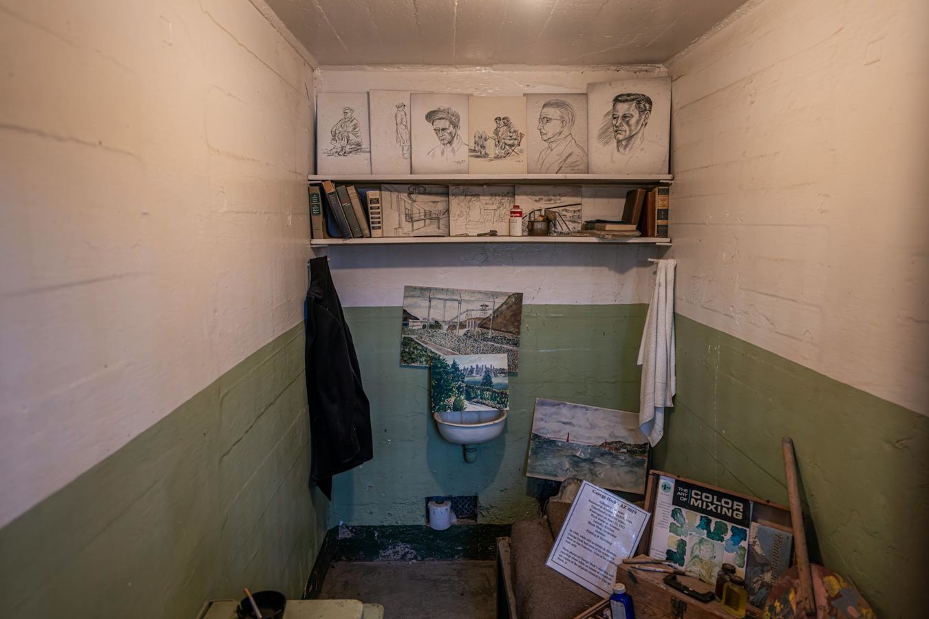 Prison cell interior displaying artwork and art materials