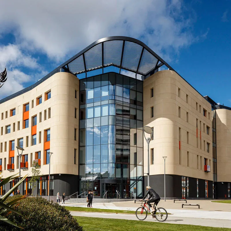 The Allam Medical Building a large modern building of light coloured brick and glass on a sunny day with blue sky