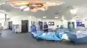 Three students in blue scrubs standing with equipment in a mock operating theatre