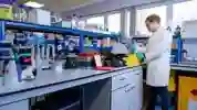 Research assistant in a lab coat performing an experiment in a lab