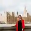 A student stood on the the banks of the thames with Westminster behind.
