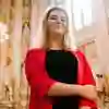 A female Politics student with blonde hair in a red blazer standing in the Houses of Parliament