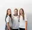 Three students hug in their sports uniform