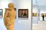 A sculpture in the library art gallery with paintings on the wall in the background
