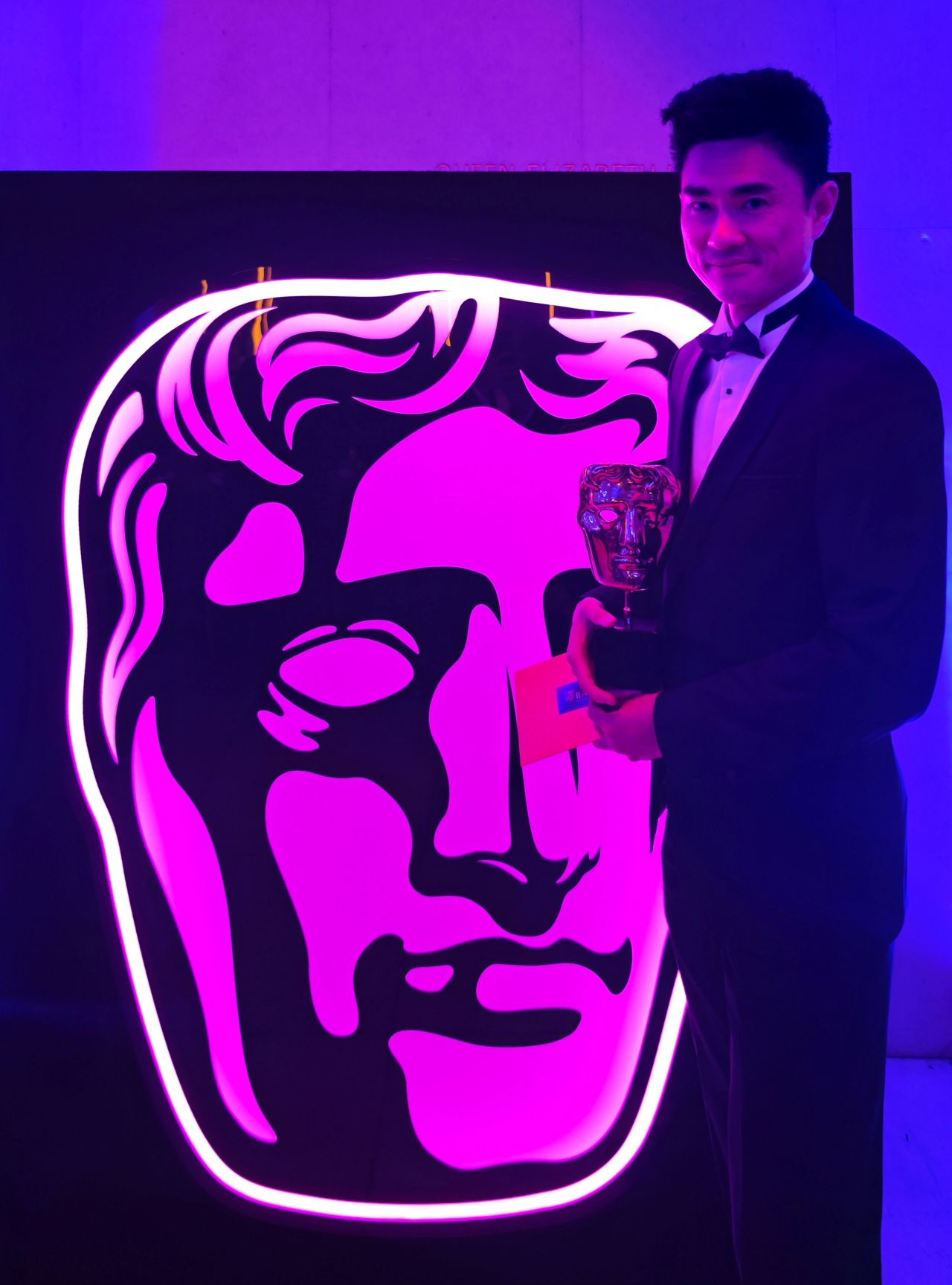 Alumni stood holding a BAFTA.