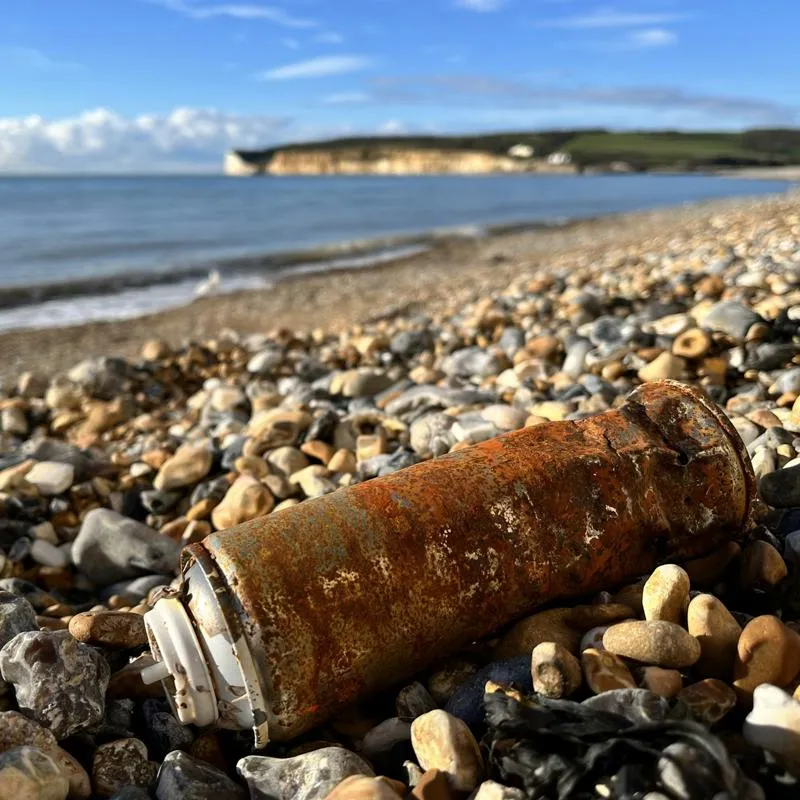 A rusted aerosol can in the foreground of a beach scene