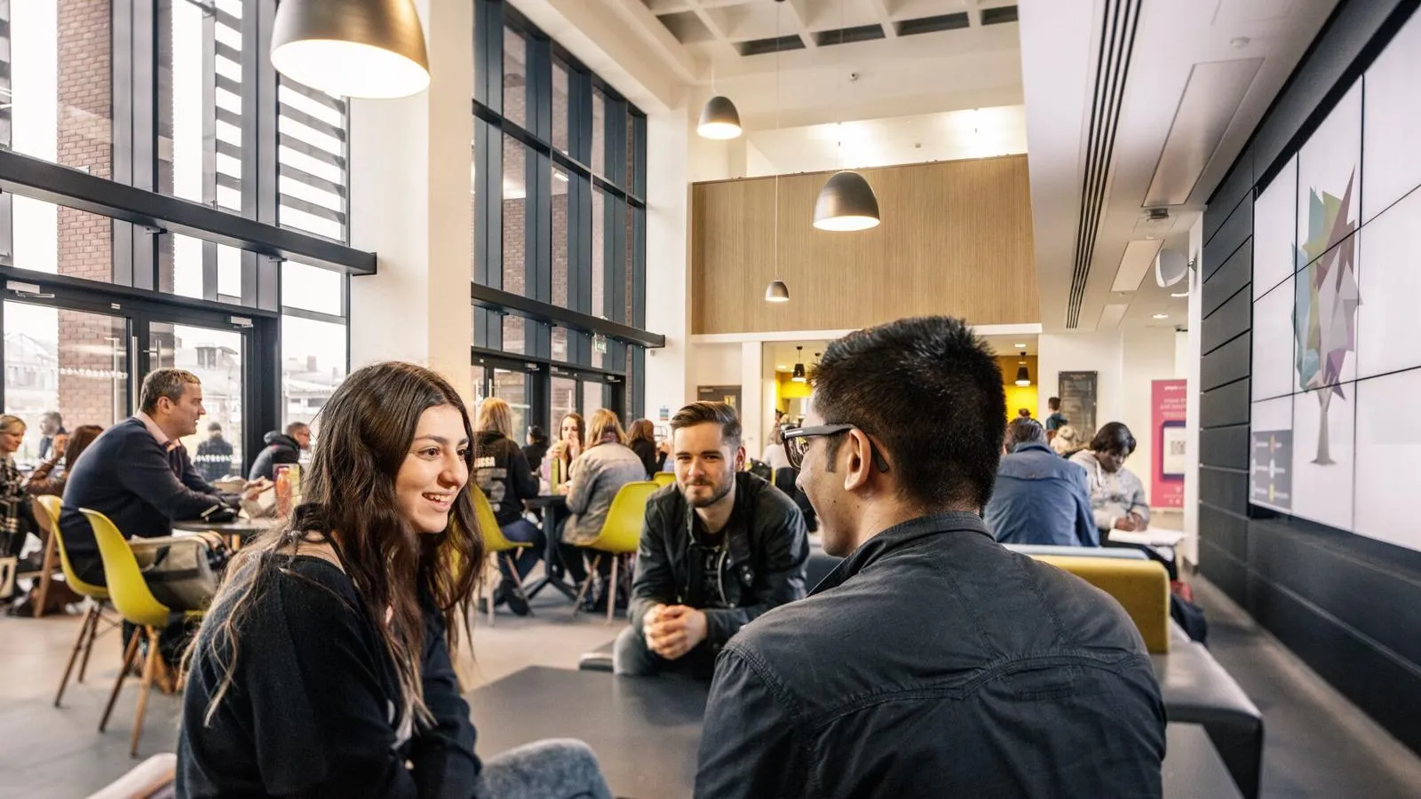 A busy library cafe with groups of students chatting and socialising