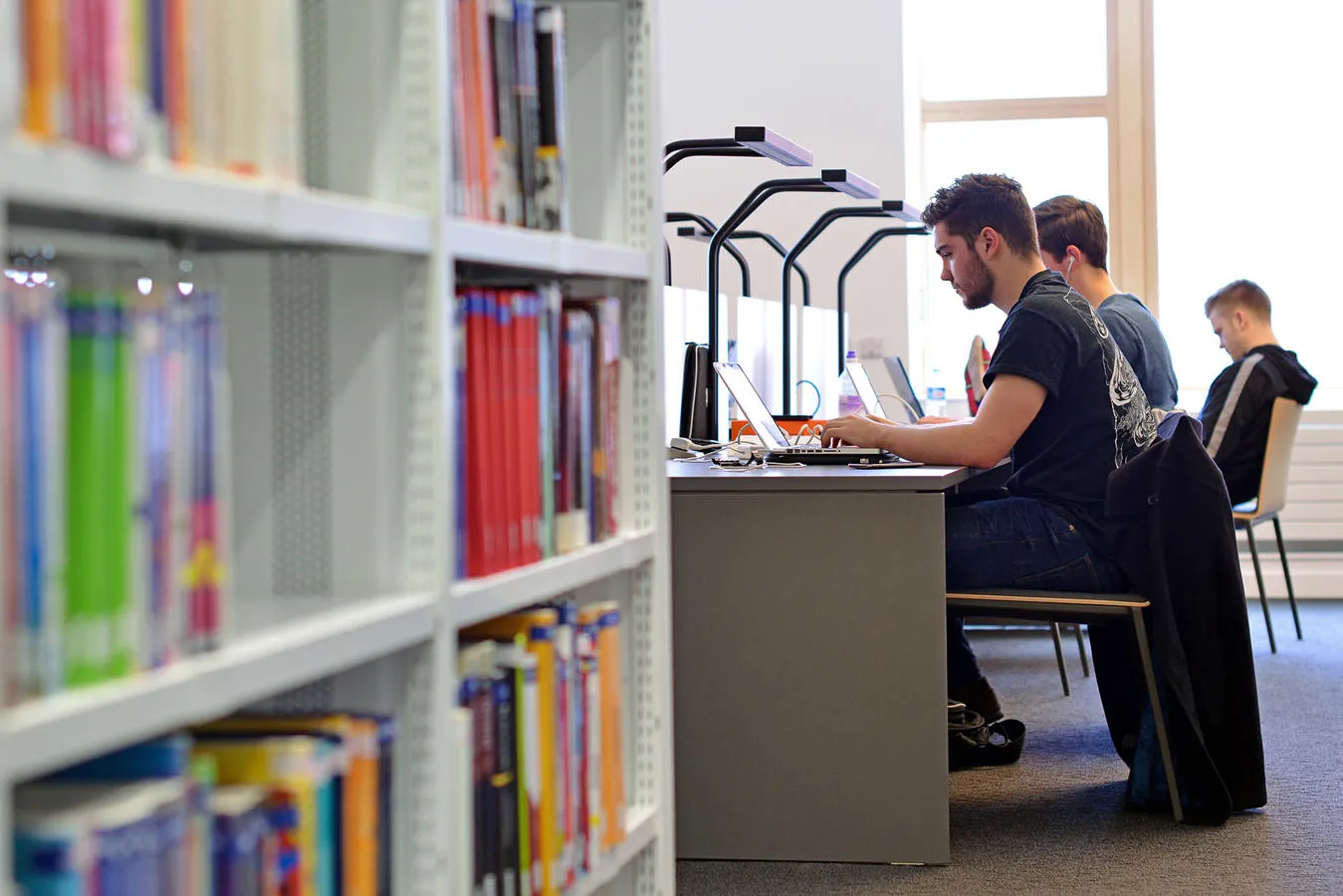 Student working on a computer at a desk in a library