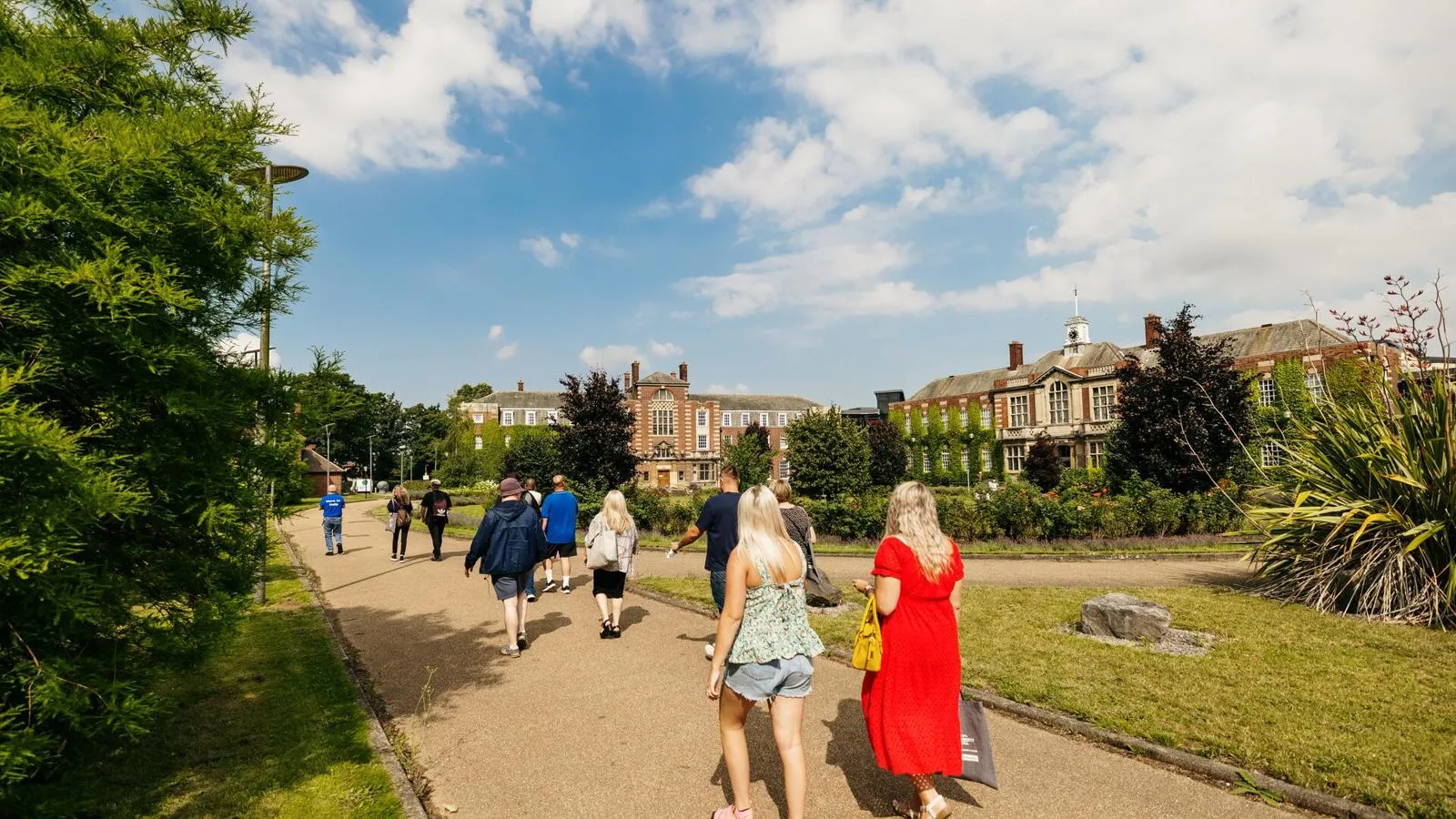 People walking on paths between lawns outside grand University of Hull building.