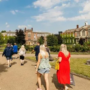 People walking on paths between lawns outside grand University of Hull building.