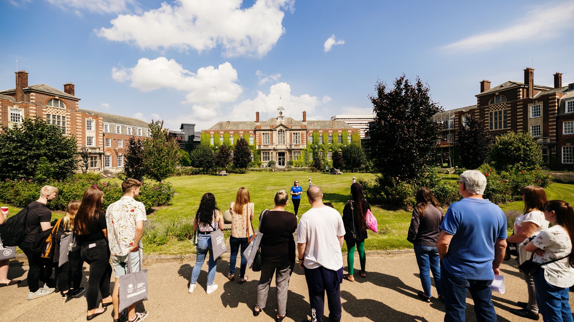 Prospective students and parents stand watching a student ambassador giving a tour in the Rose Bowl