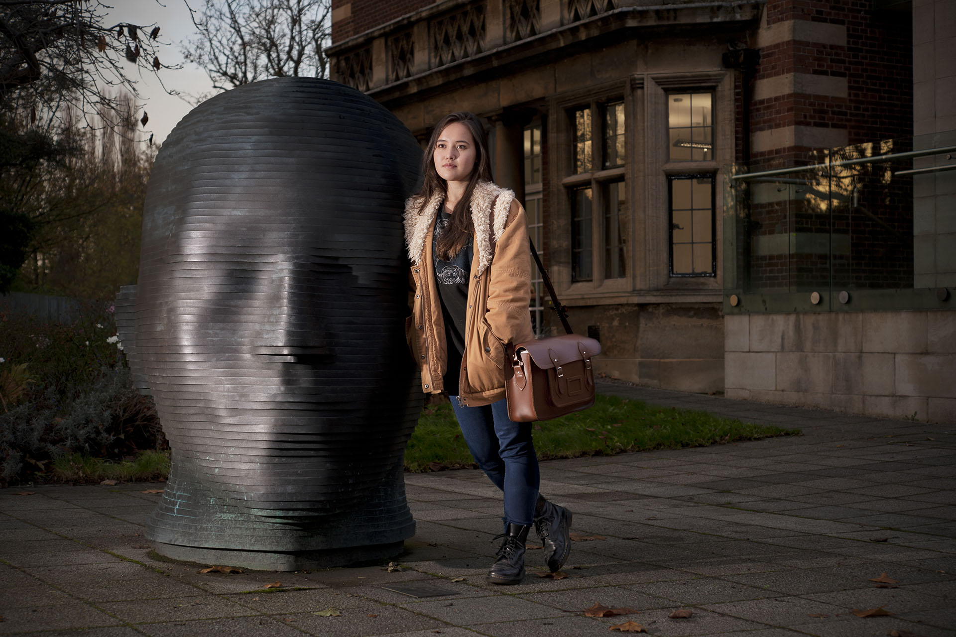 Philosophy student Carolyn Ward leaning against head sculpture at the University of Hull campus