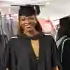 Female student smiling at camera in a cap and gown celebrating graduation
