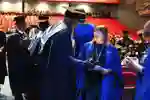 Student talking to staff member on graduation stage