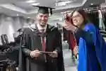 Student  holding graduation booklet and staff member pointing out directions