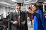 Student holding graduation booklet and staff member pointing out directions