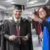 Student holding graduation booklet and staff member pointing out directions
