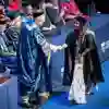 Student shaking hands with robed University chancellor on the graduation stage