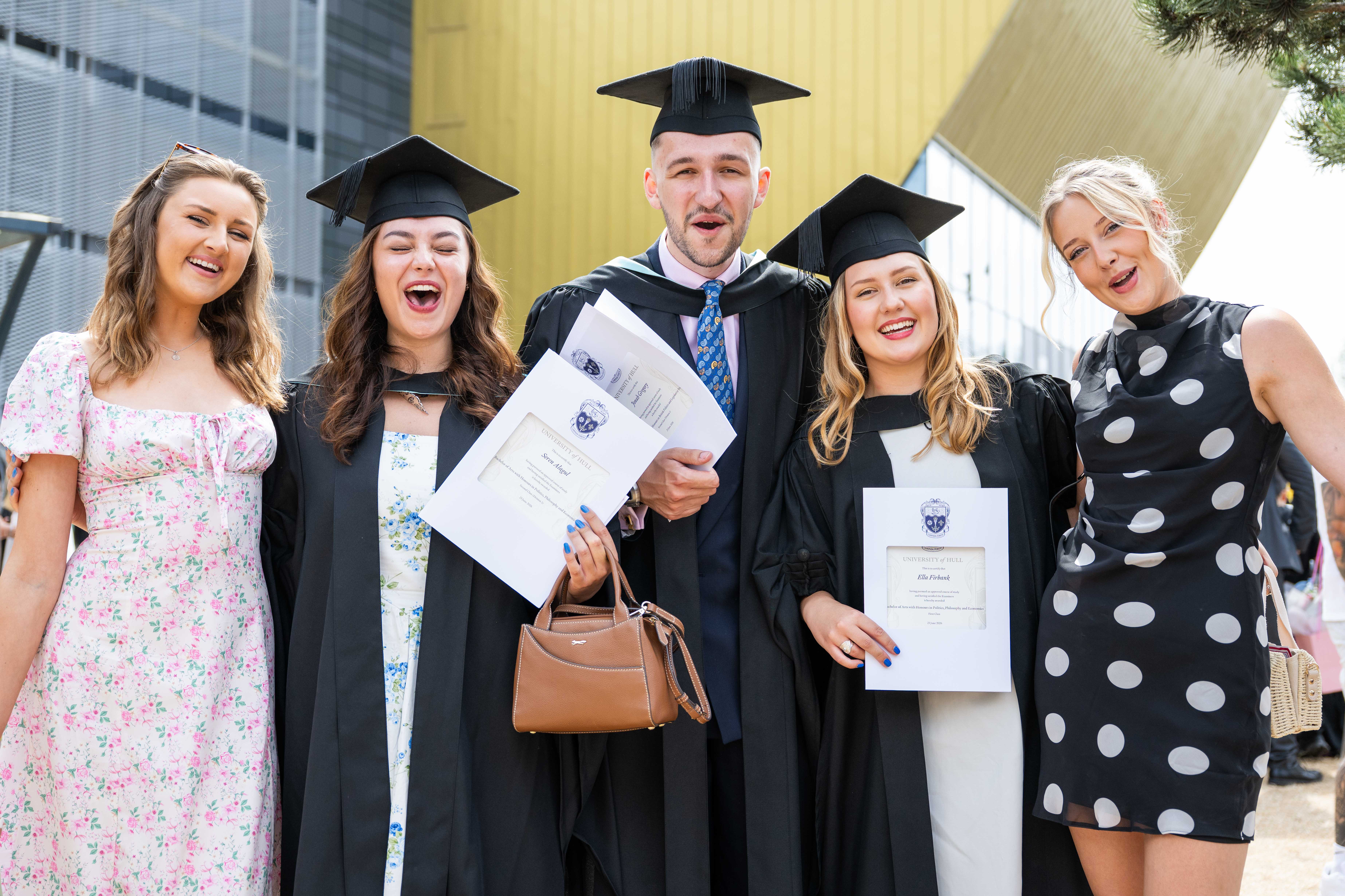 Three graduates celebrate with friends. 