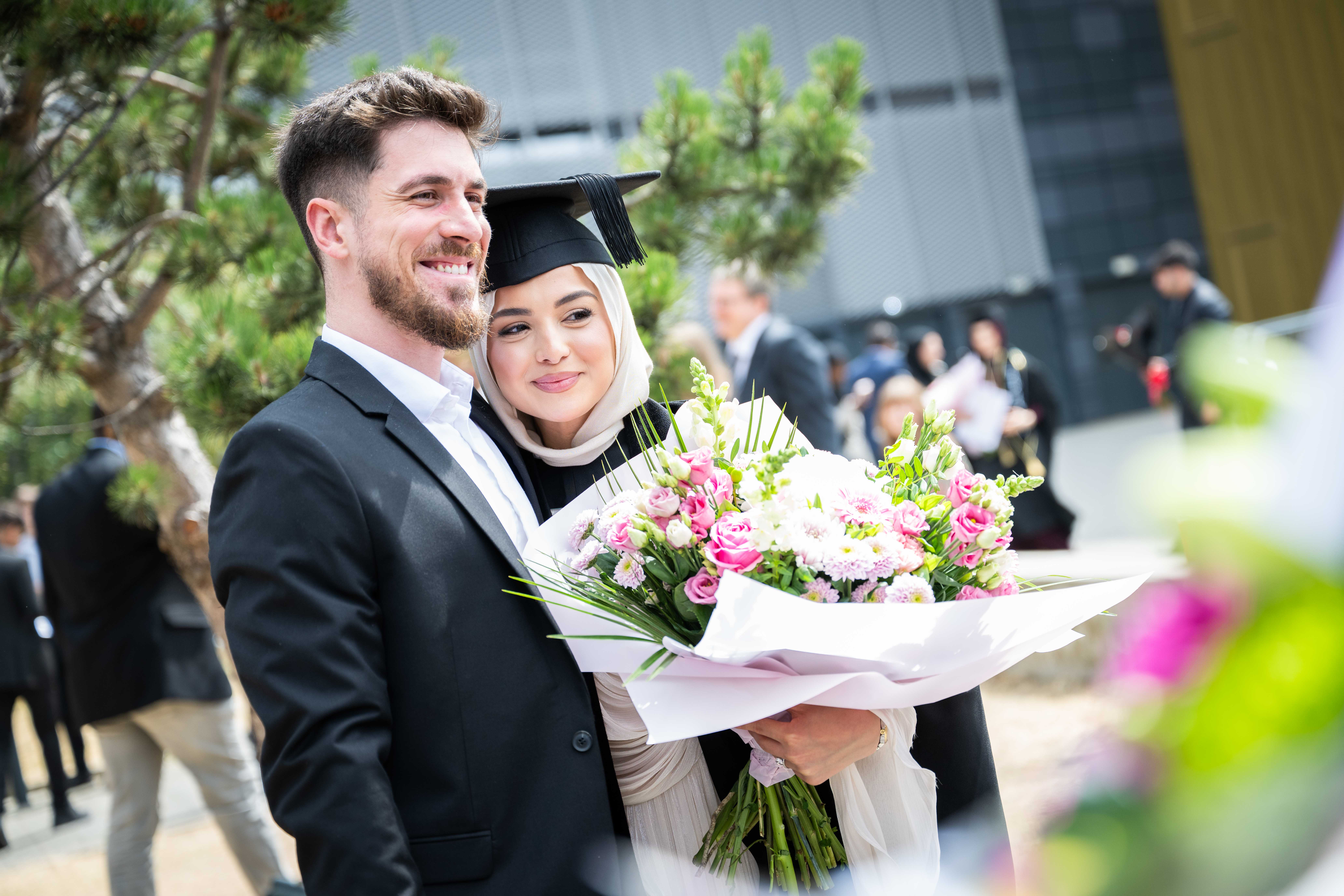 Female graduate with ceremonial flowers. 