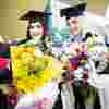 Graduates with bouquets of flowers.