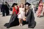 Two students posing with child for family graduation photo