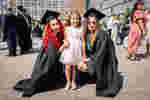 Two students posing with child for family graduation photo