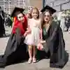 Two students posing with child for family graduation photo