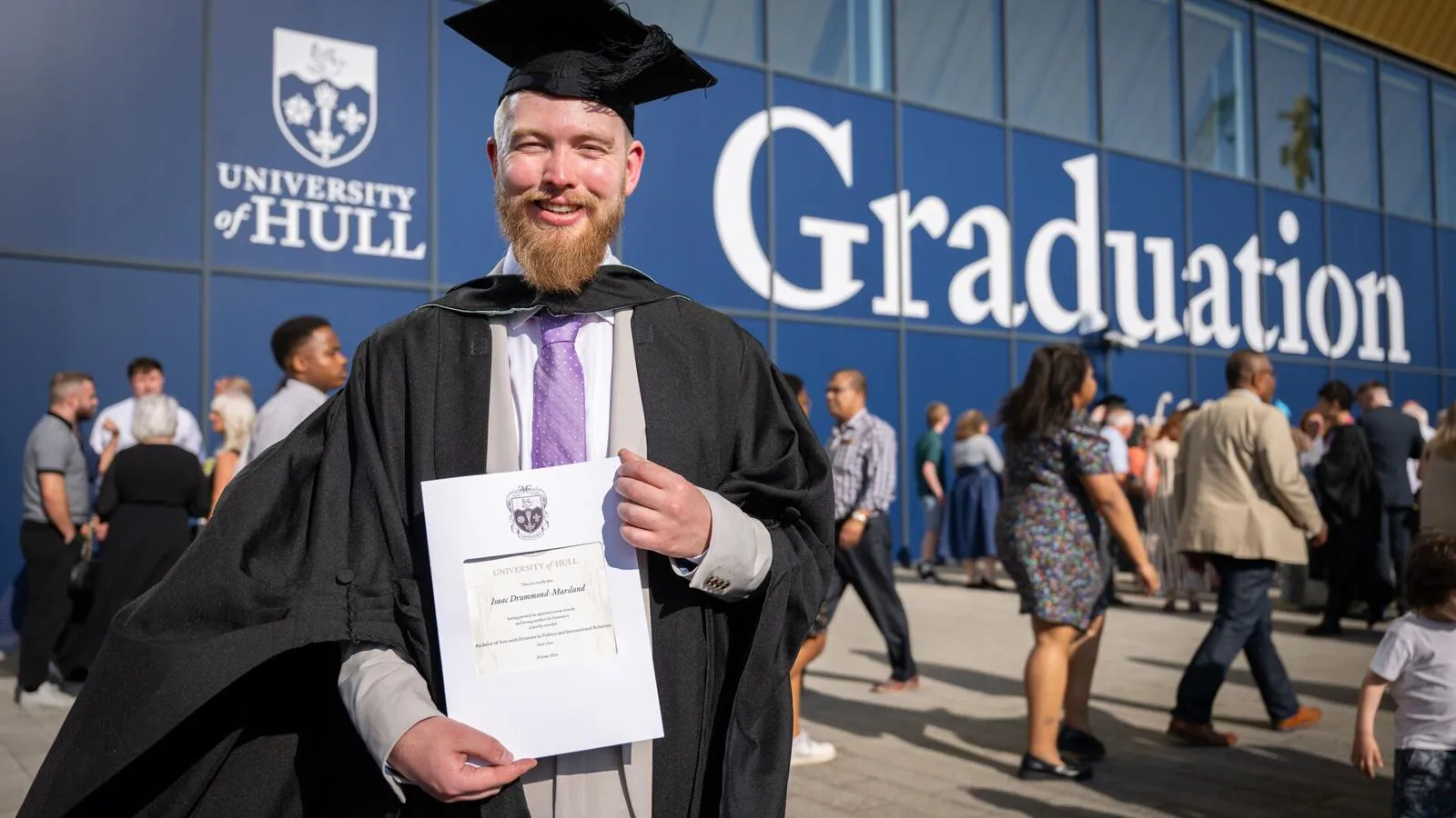 Gowned student holding his graduation certificate