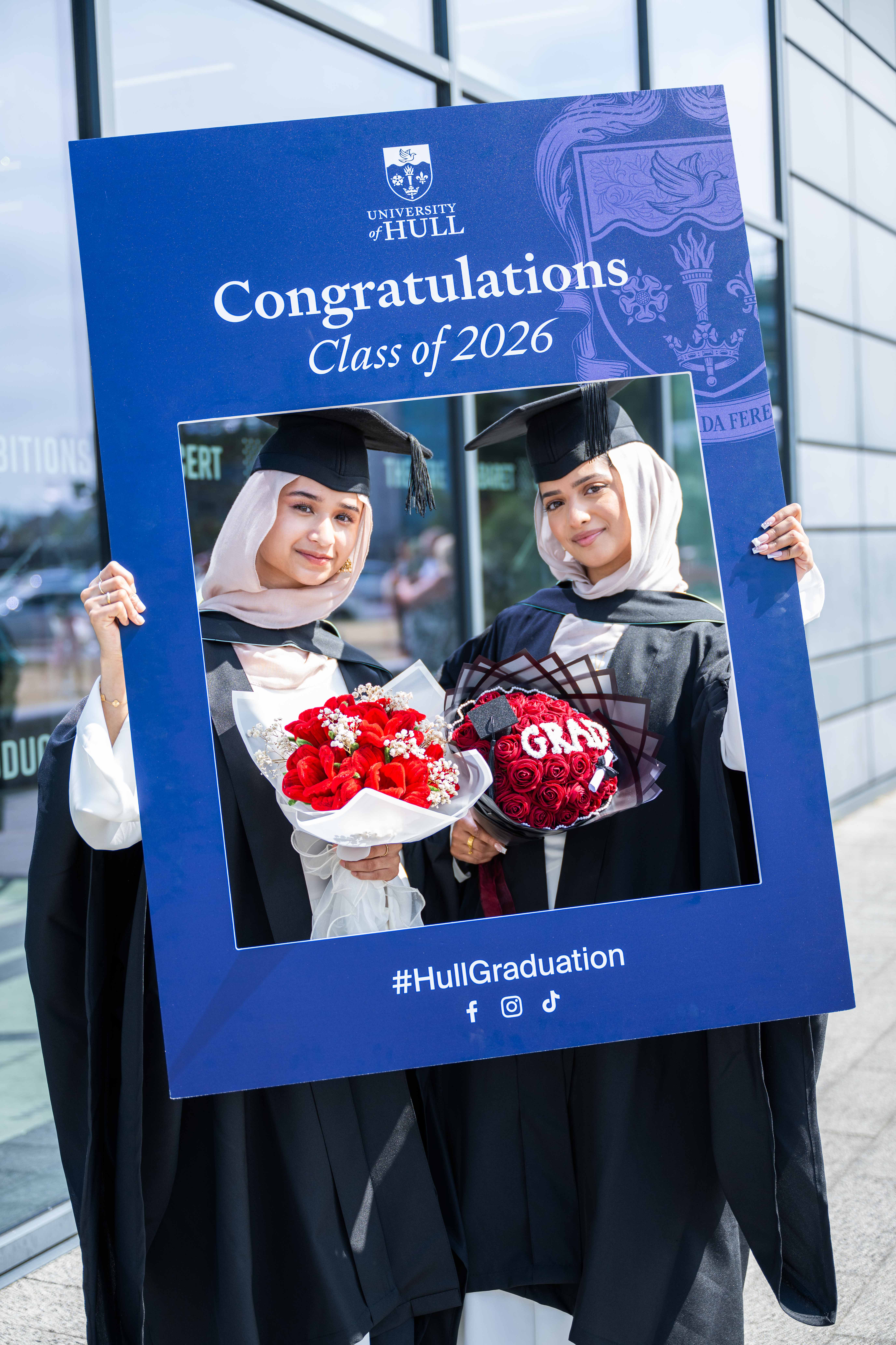 Two students with bouquets of flowers. 