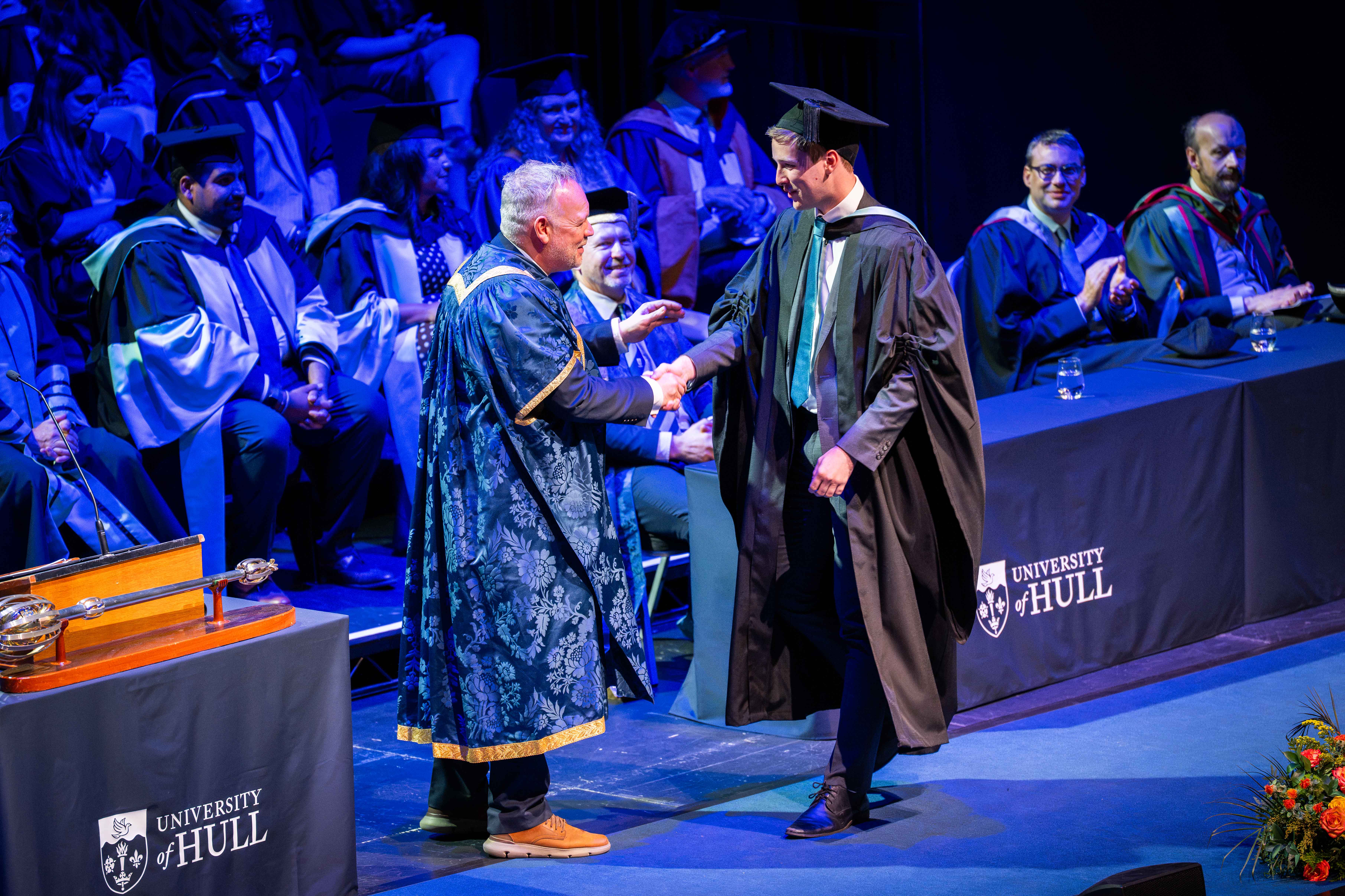Recent graduates shakes hand with Vice Chancellor Tom Lawson. 