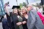 Student taking a selfie with parents at graduation