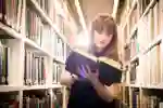 Student reading a book in library racks