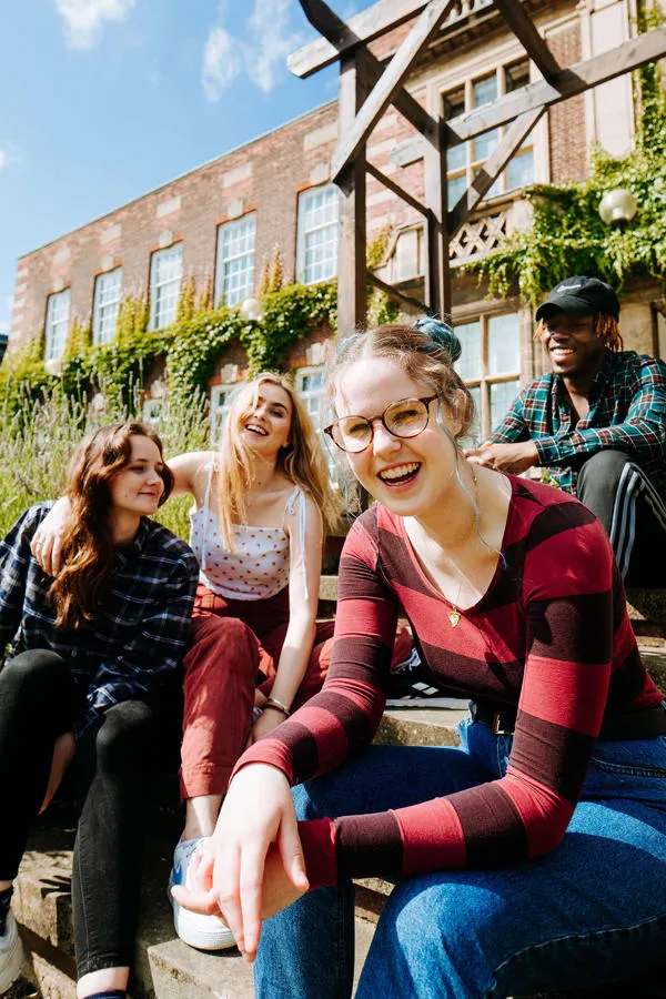 Four students laughing together on University of Hull campus.