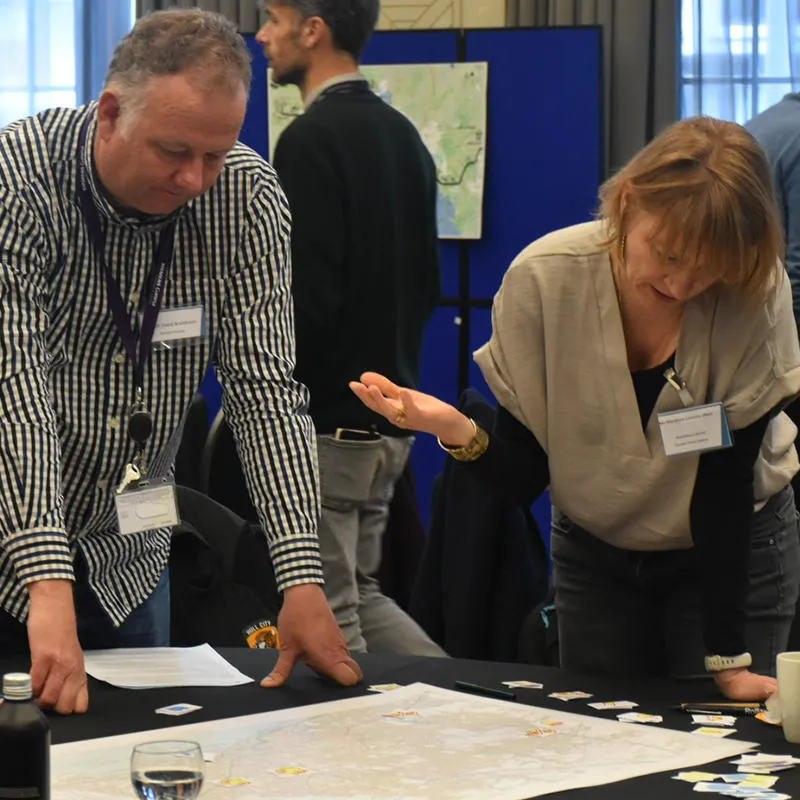 Three workshop attendees gather around a map