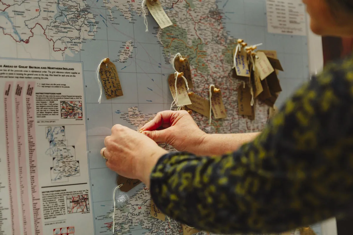 Someone attaching handwritten labels to locations on a UK map 