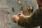 Someone attaching handwritten labels to locations on a UK map
