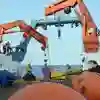 Scientists on a research vessel stand by two orange cranes