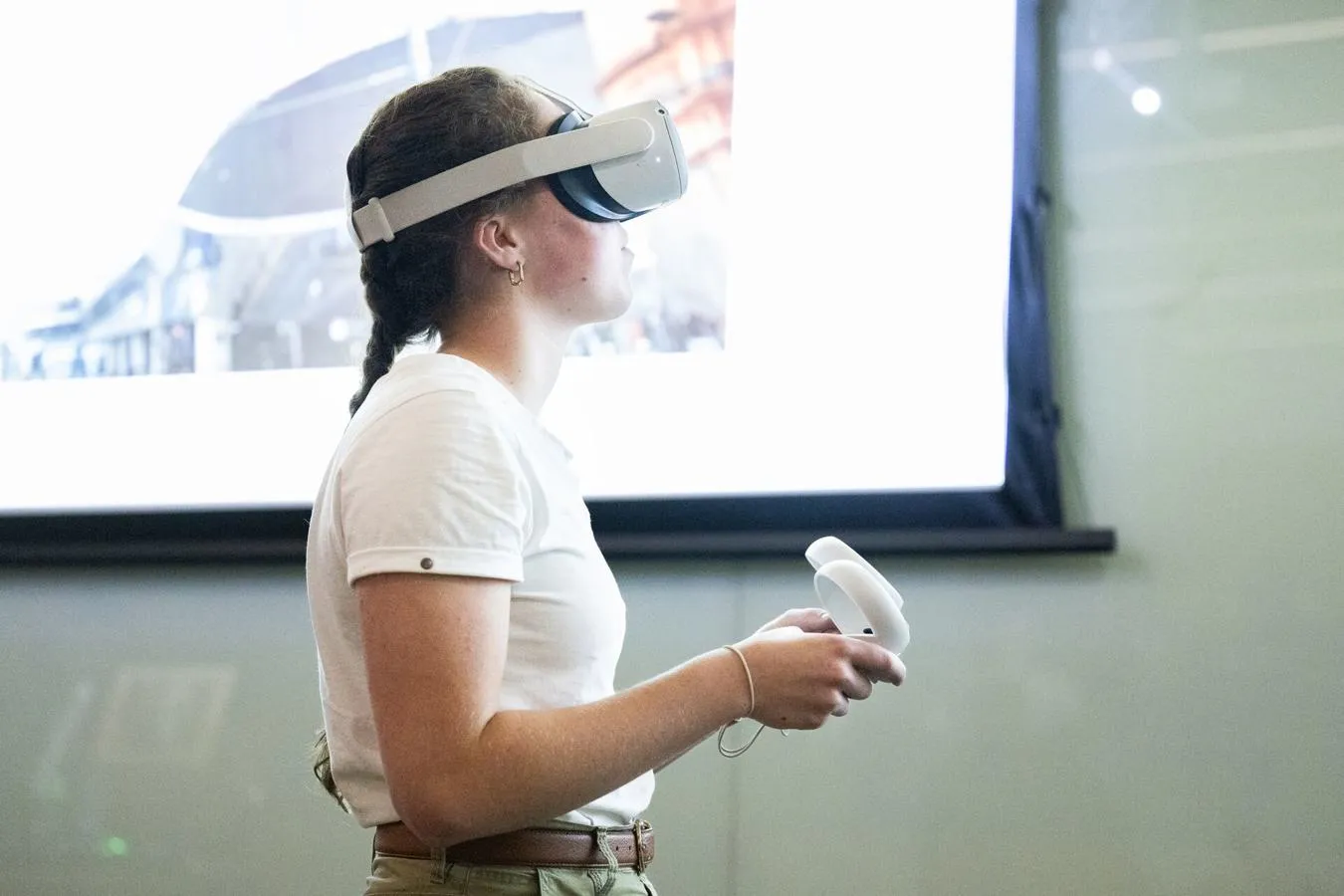 A female student wearing wearing a VR headset and holding controllers in a Criminology class