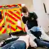 Kneeling student paramedic uses a breathing mask on a mannequin