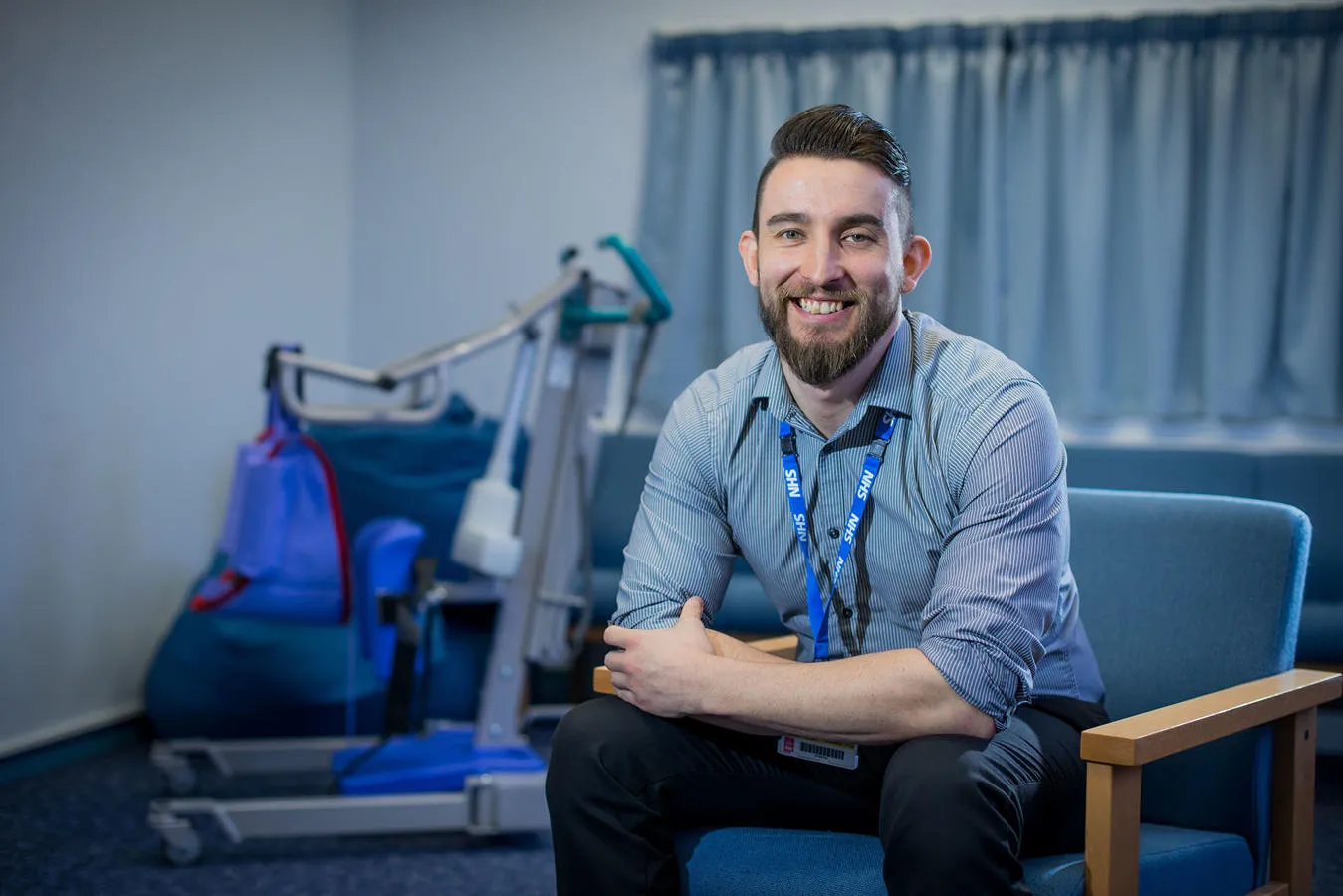 Man wearing an NHS lanyard seated in a chair 