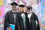 Three robed students posing for graduation photo