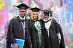 Three robed students posing for graduation photo