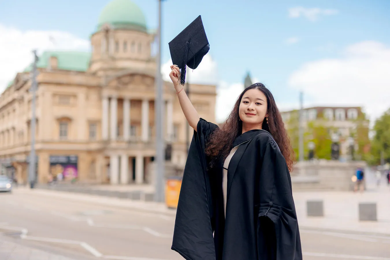 A University of Hull Graduate in cap and gown outside city hall in Hull