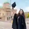 A University of Hull Graduate in cap and gown outside city hall in Hull